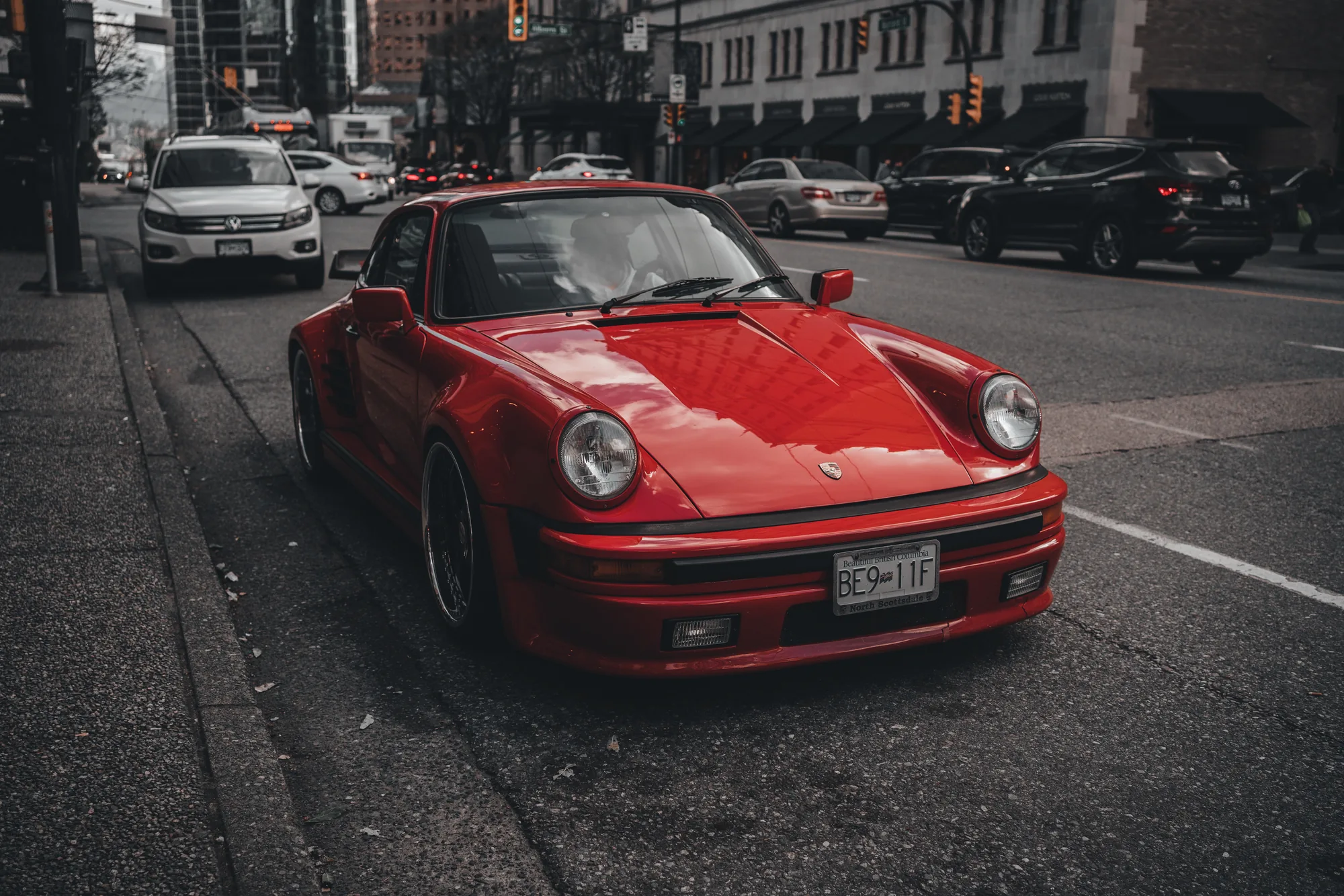 A red vintage Porsche 911 parked on a city street